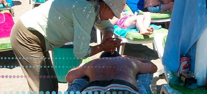 Persona haciendo un masaje a otra en la playa